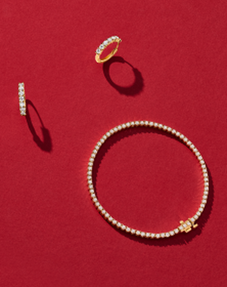 Birks diamond and yellow gold jewellery on a red background.