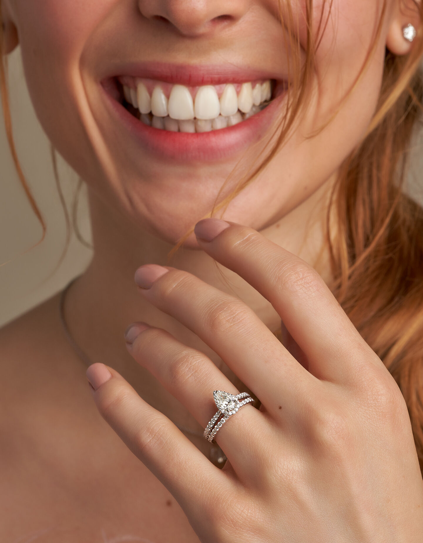 A woman smiling with a Birks diamond engagement ring and wedding band.