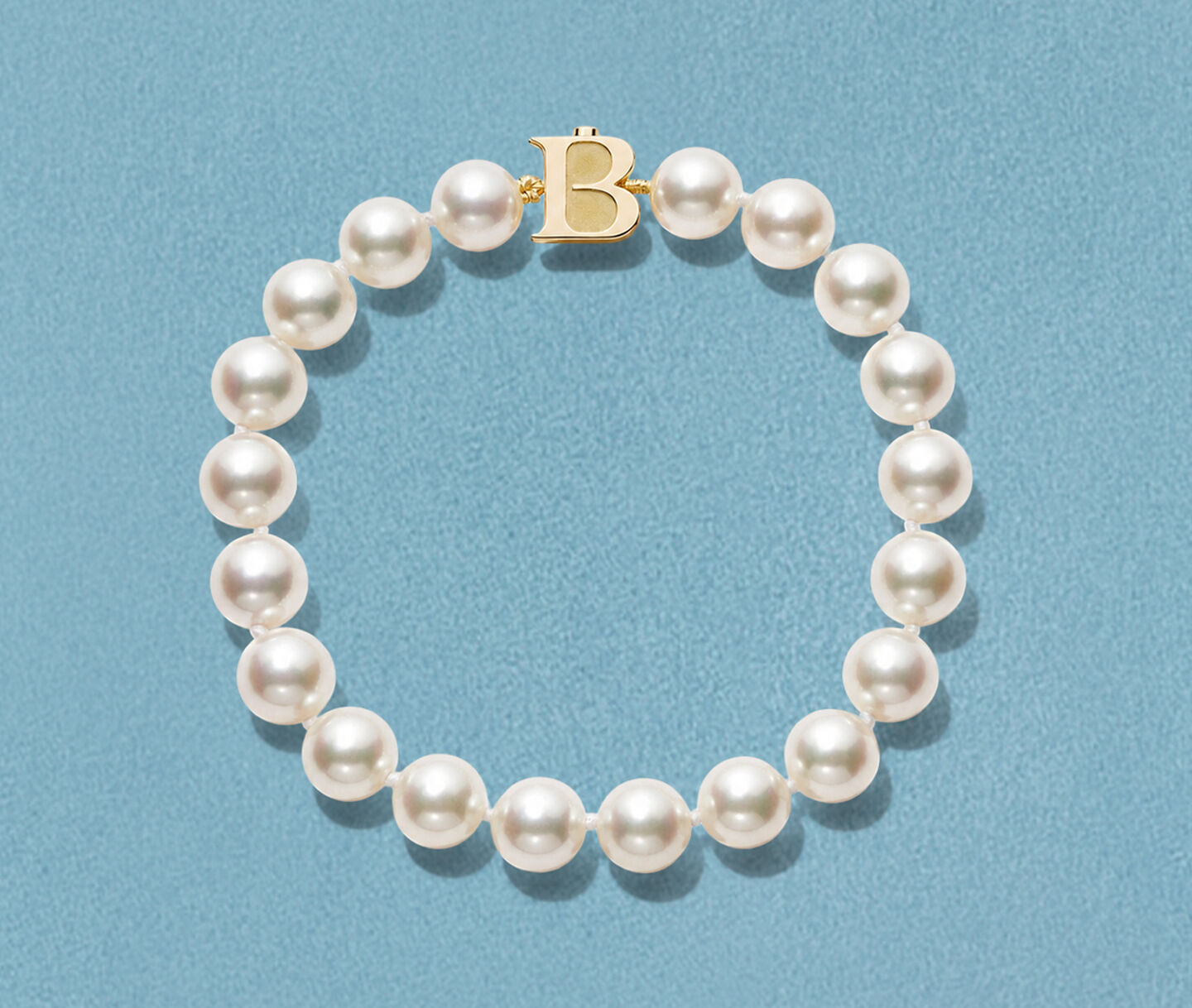 Birks Pearls Akoya pearl bracelet on a blue background.