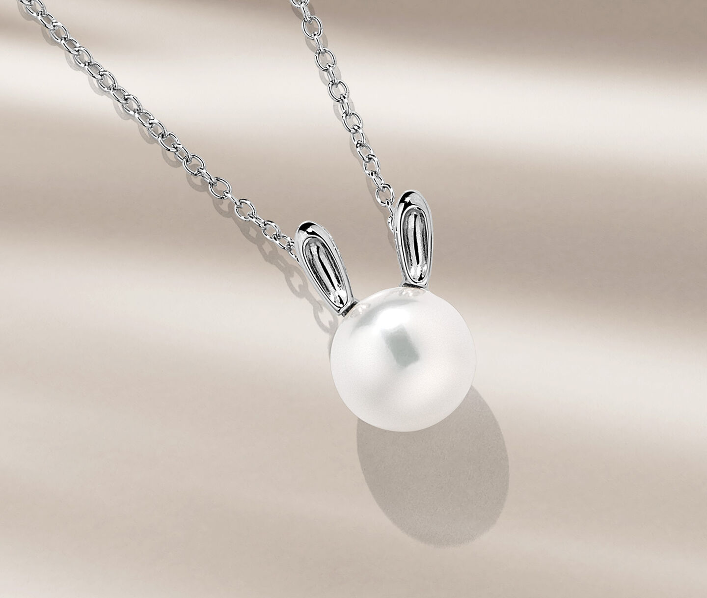 Birks Essentials hare pearl pendant on a beige background.