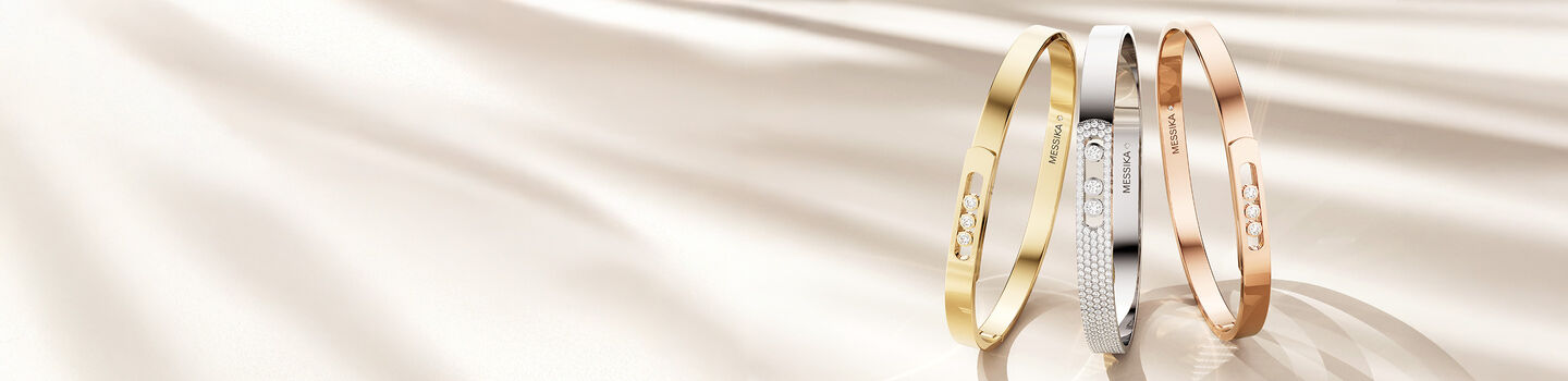 Messika diamond and gold bracelets on a beige background.
