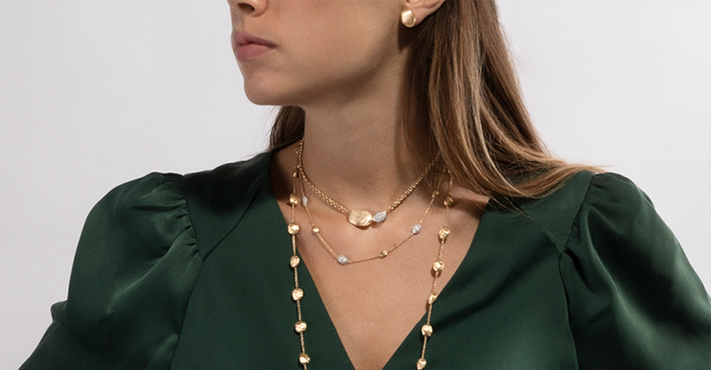 Model in a green shirt wearing multiple Marco Bicego Siviglia necklaces