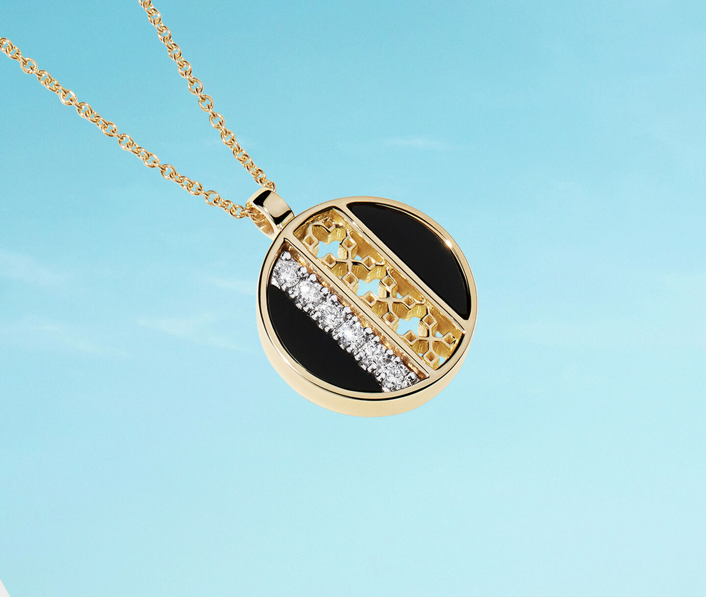 Birks Dare to Dream onyx and diamond yellow gold medallion on a blue background.