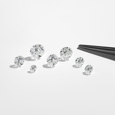 Diamant brut de différents poids en carats sur un fond gris clair.