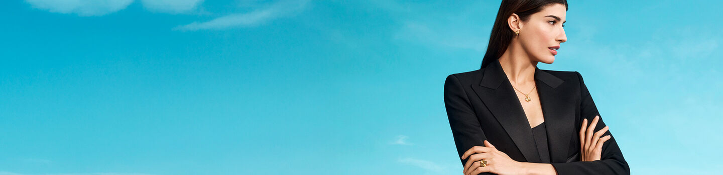 A woman wearing Birks Muse jewellery on a blue background.