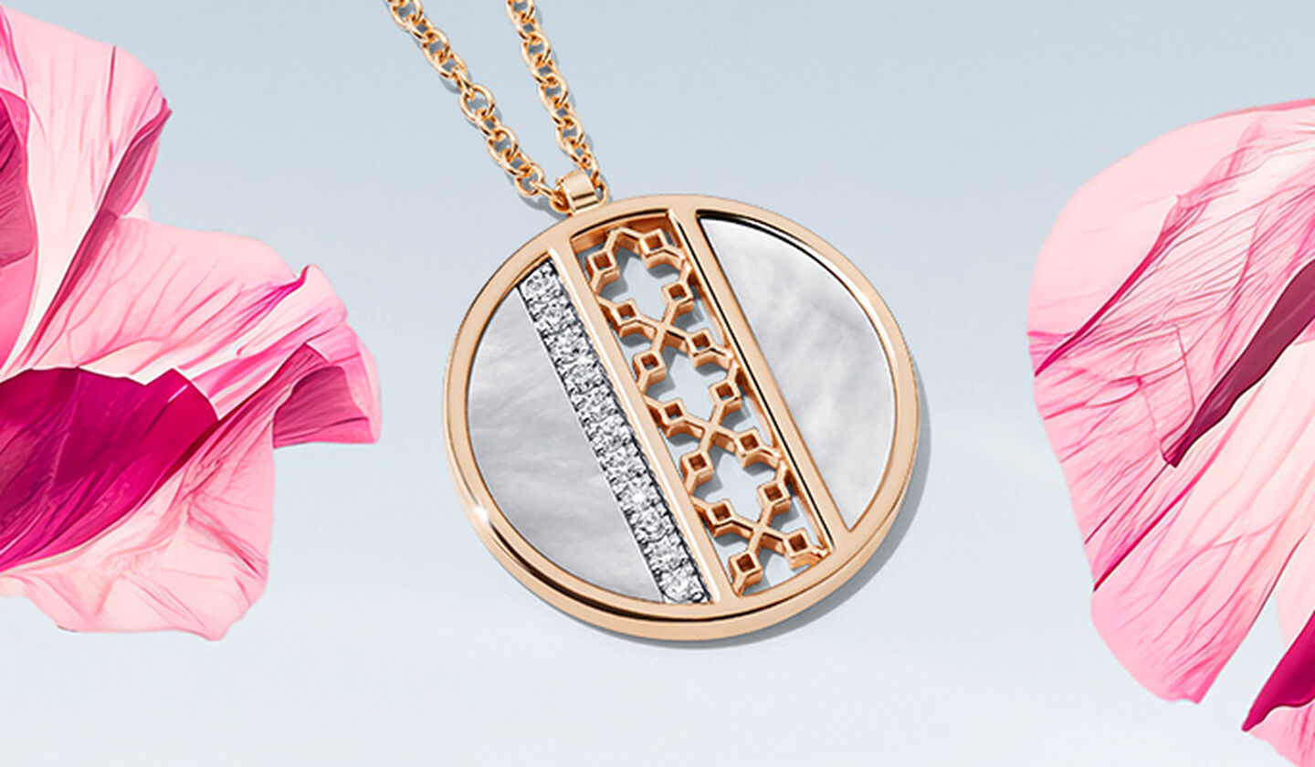 A Birks Dare to Dream mother-of-pearl and diamond medallion on a pink flower and light sky blue background.