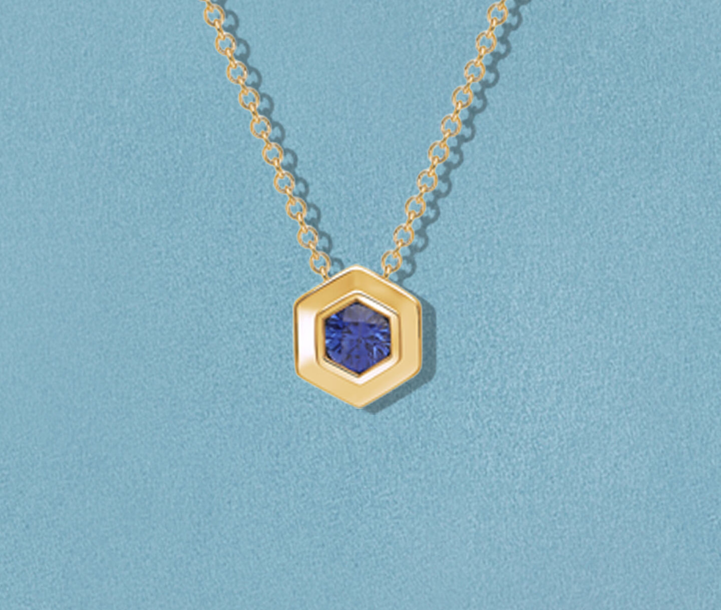 Collier Birks Bee Chic en or jaune avec saphir sur un fond bleu.