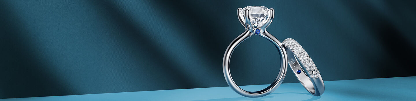 Three Birks engagement rings on a blue background.