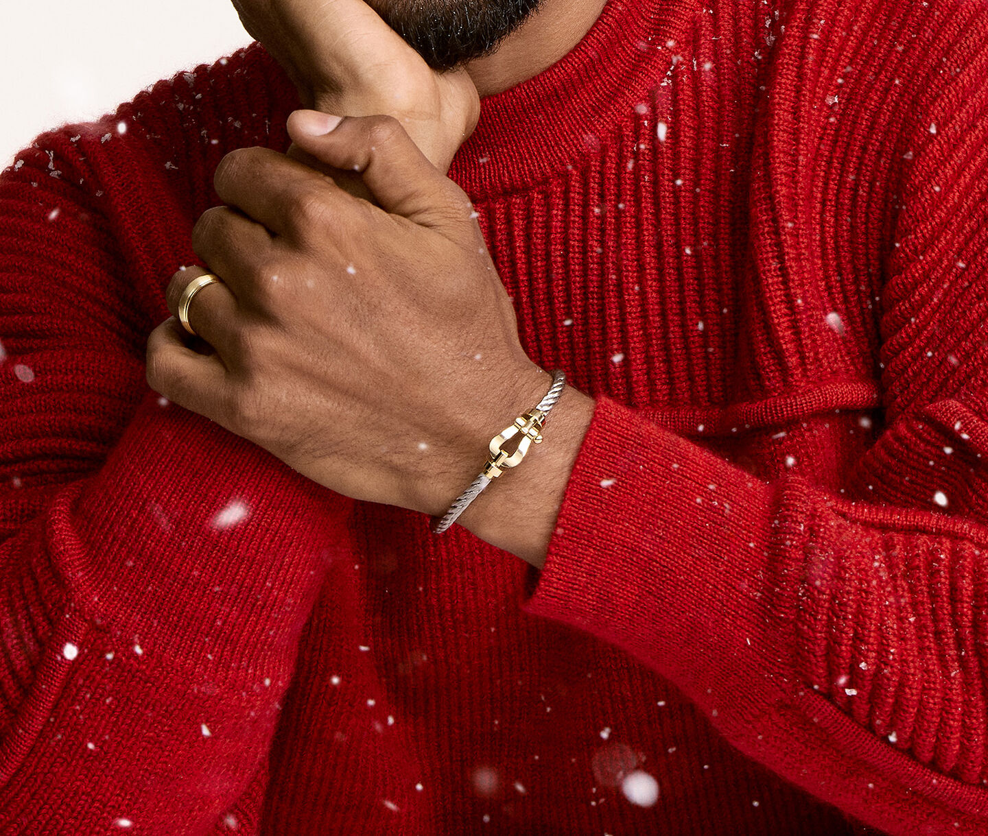 A person wearing Fred force 10 cable bracelet on a beige snowy background.