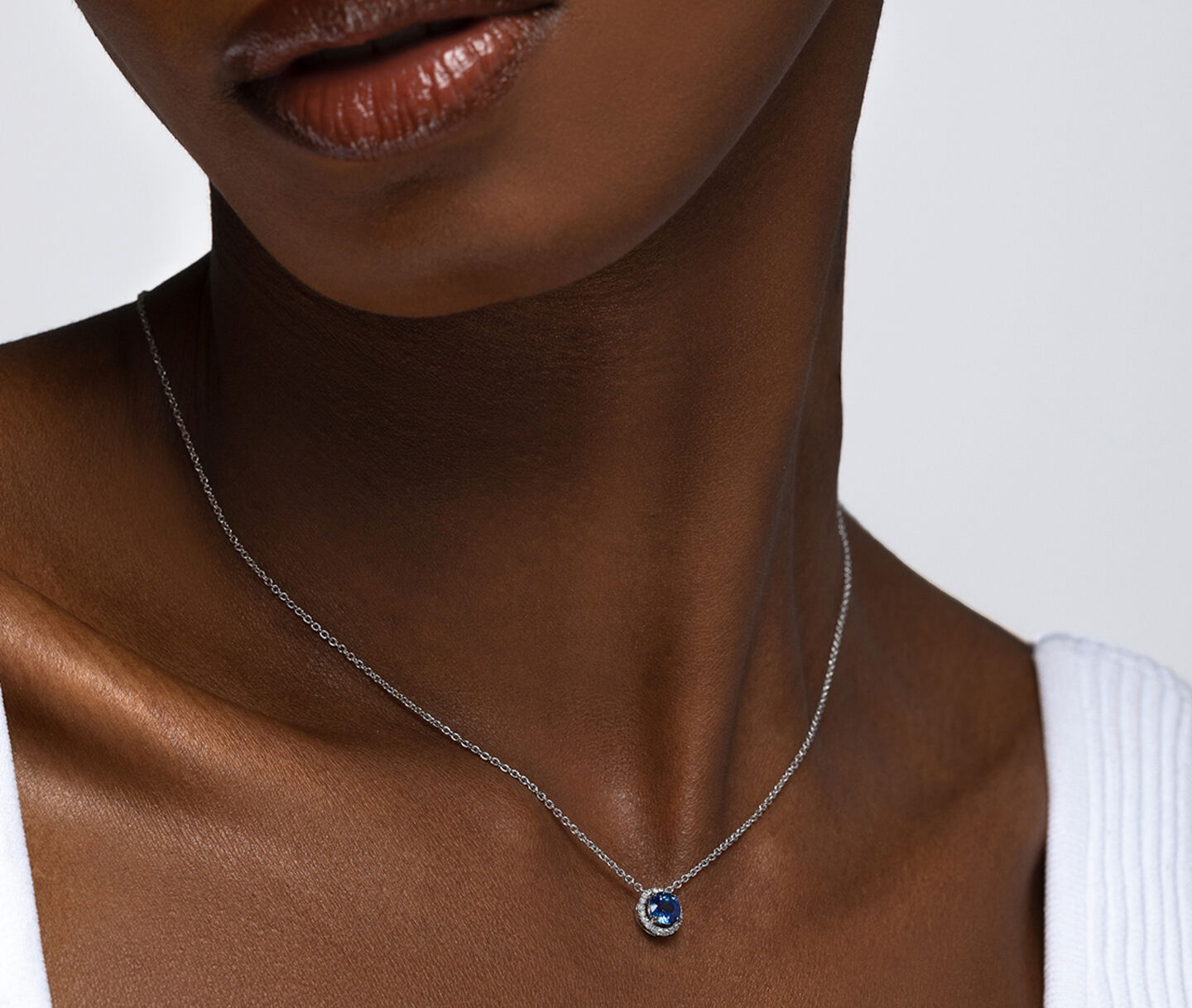 A woman wearing a Birks Rosée du Matin sapphire and diamont pendant.