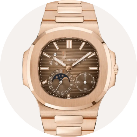 Montre Patek Philippe en or rose sur un fond beige.