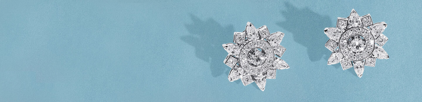 Birks Snowflake High Jewellery diamond earrings on a blue background.