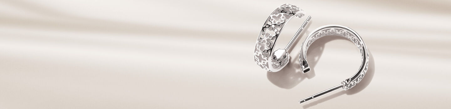 Boucles d'oreilles cr&eacute;oles Birks Dare to Dream en argent sur un fond beige.