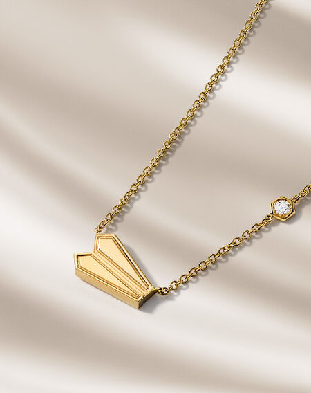 Birks Beekeeper yellow gold necklace on a beige background.