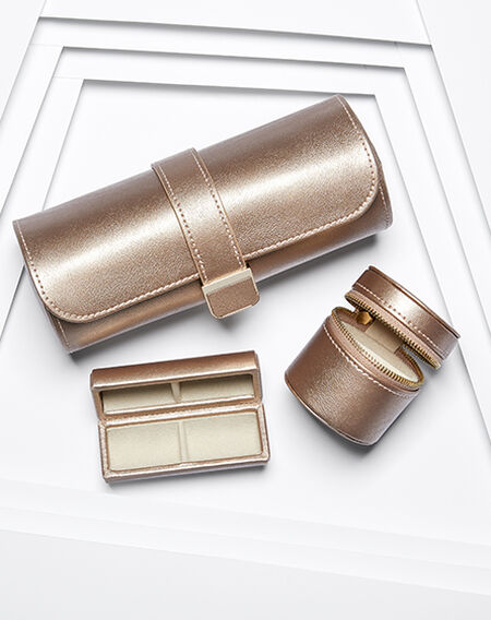 An assortment of WOLF rose gold leather travel jewellery box on a white layered background