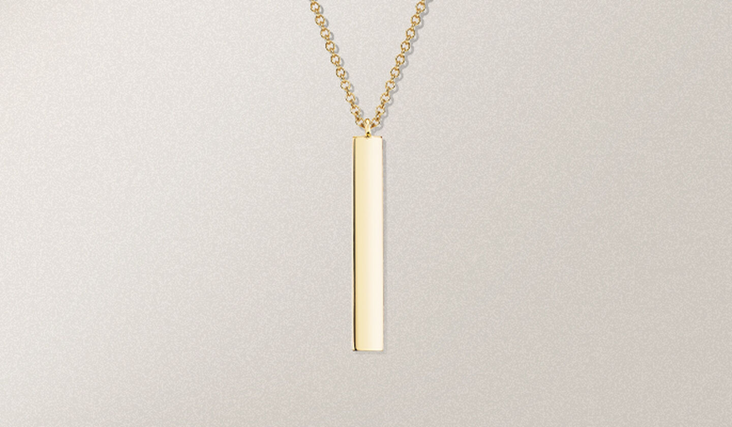 A Birks Essentials yellow gold vertical bar pendant necklace on a beige background