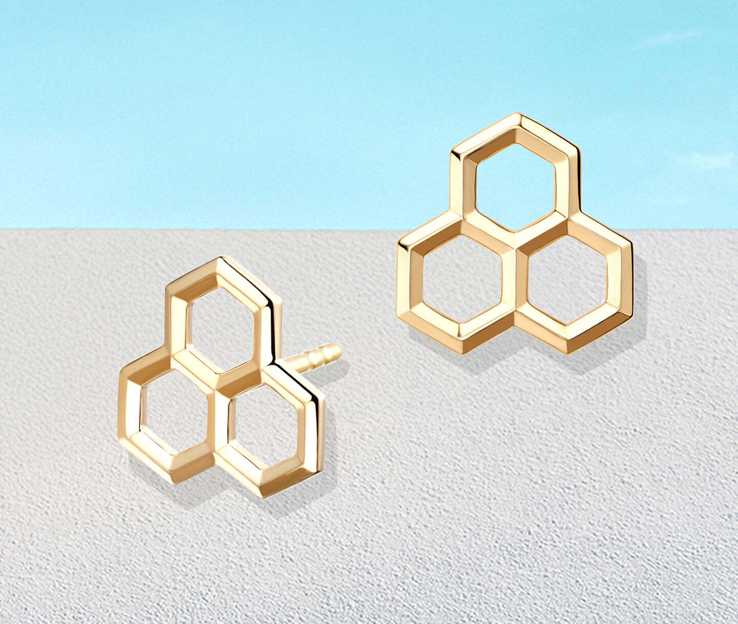 Birks Rosee du Matin yellow gold earrings on a blue background.