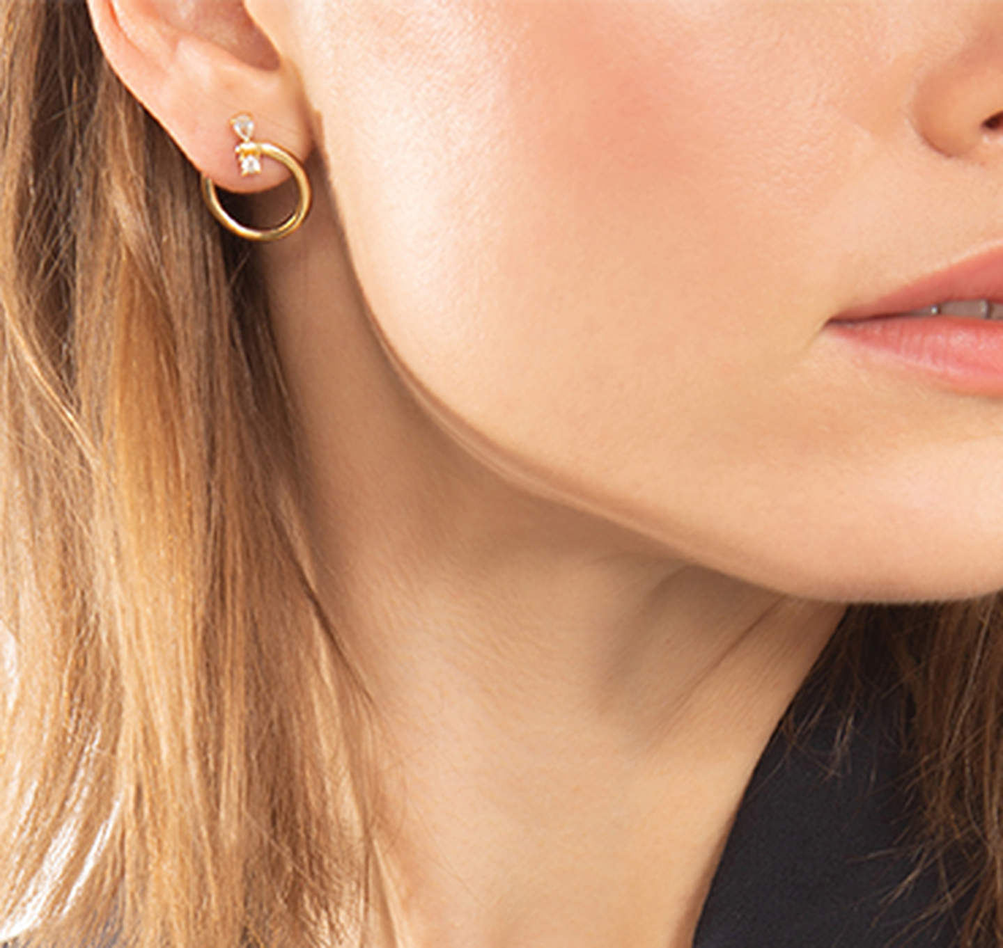 Une femme porte les boucles d'oreilles en or jaune de Monica Rich Kosann.