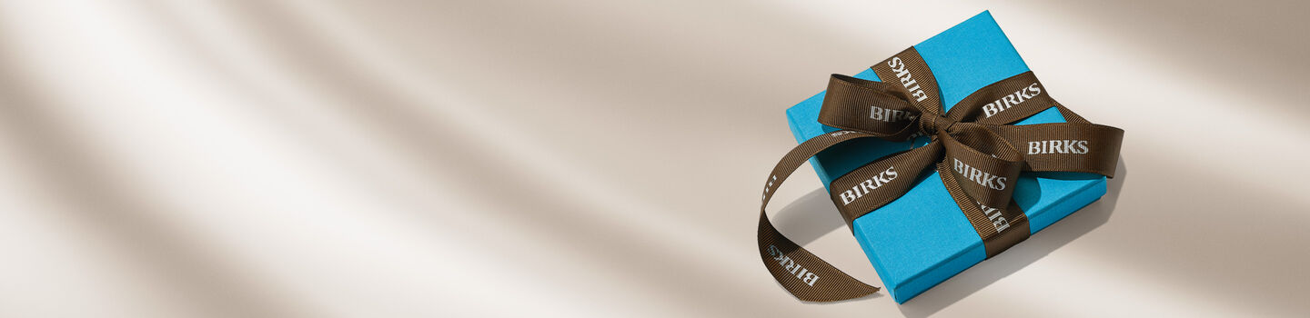A Maison Birks blue box on a beige background.