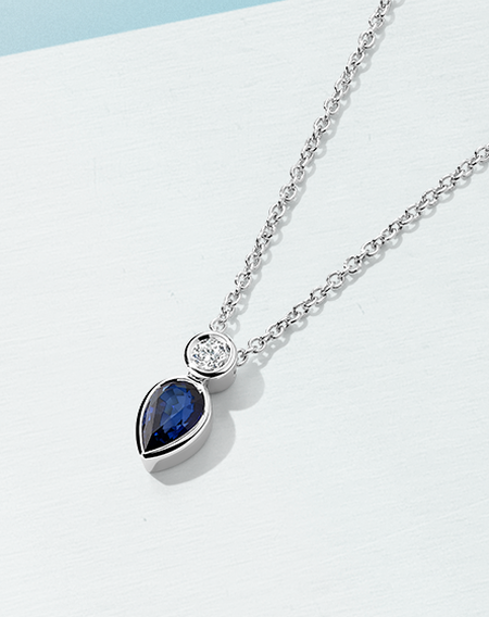 Collier Birks Splash avec saphir et diamant sur un fond bleu.