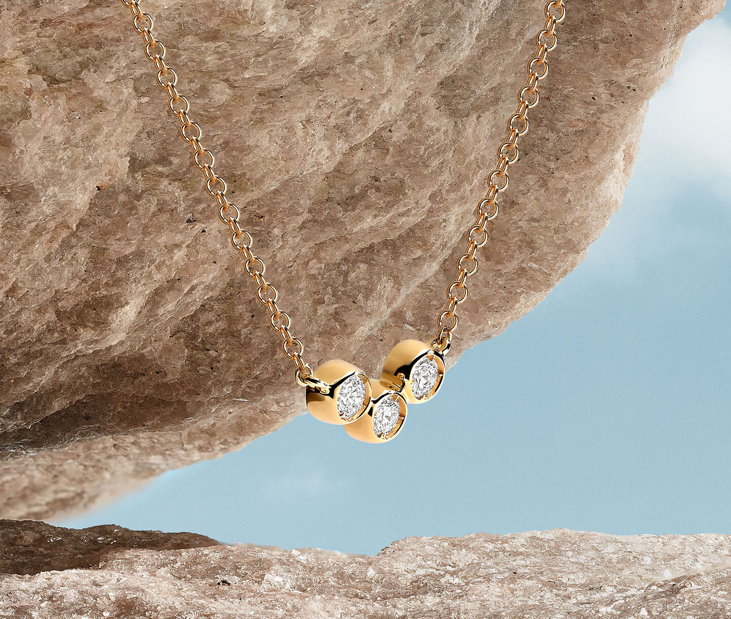 A Birks Iconic Splash pendant in rose gold with diamonds hanging off a rock.