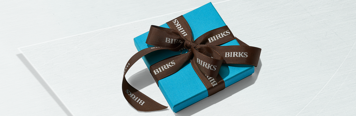 Maison Birks blue box wrapped in brown ribbon.