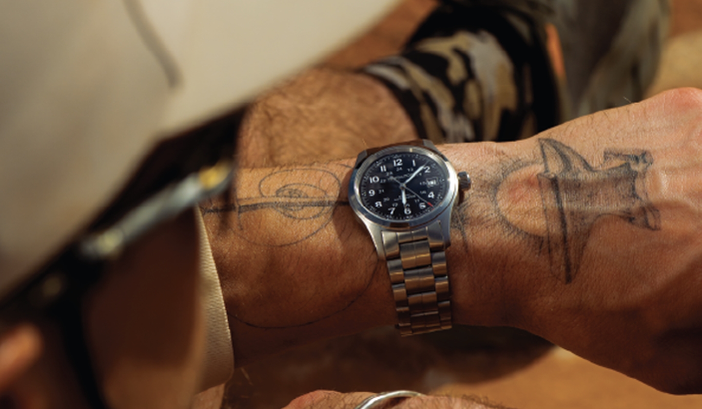 A man wearing a Khaki Field watch by Hamilton.