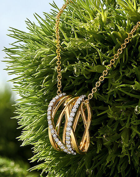 Birks Rosée du Matin diamond and yellow gold pendant on a green grass background