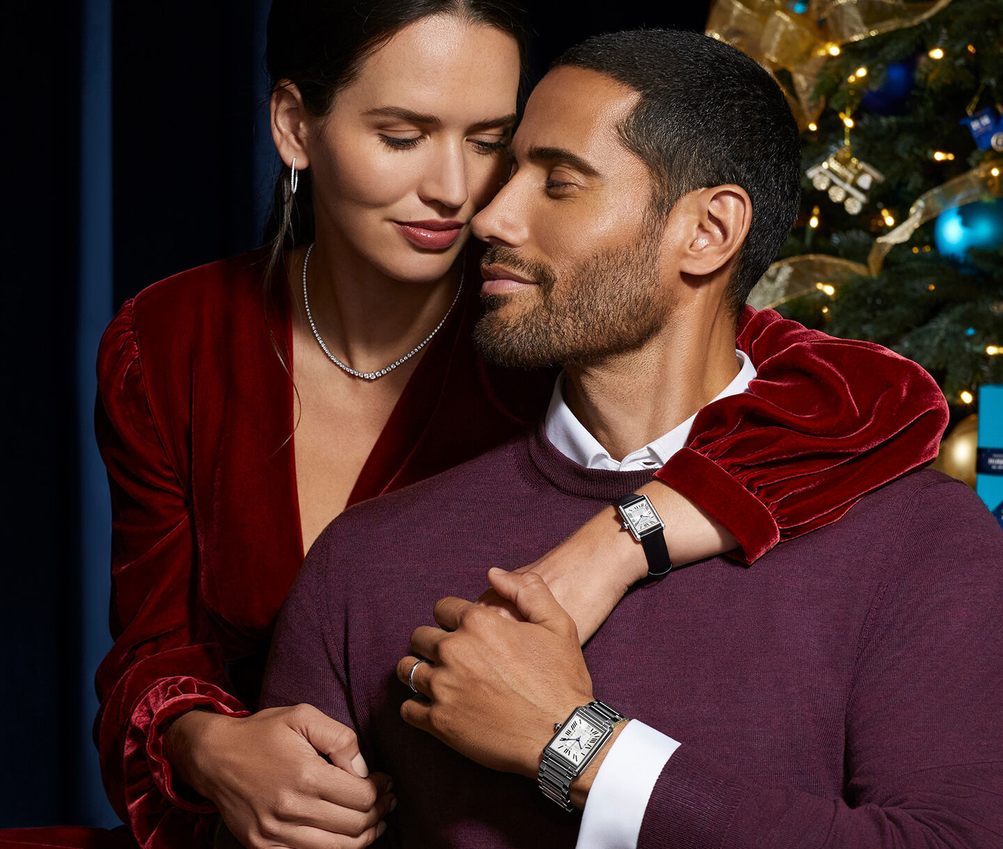 A man and woman embrace while wearing matching watches.