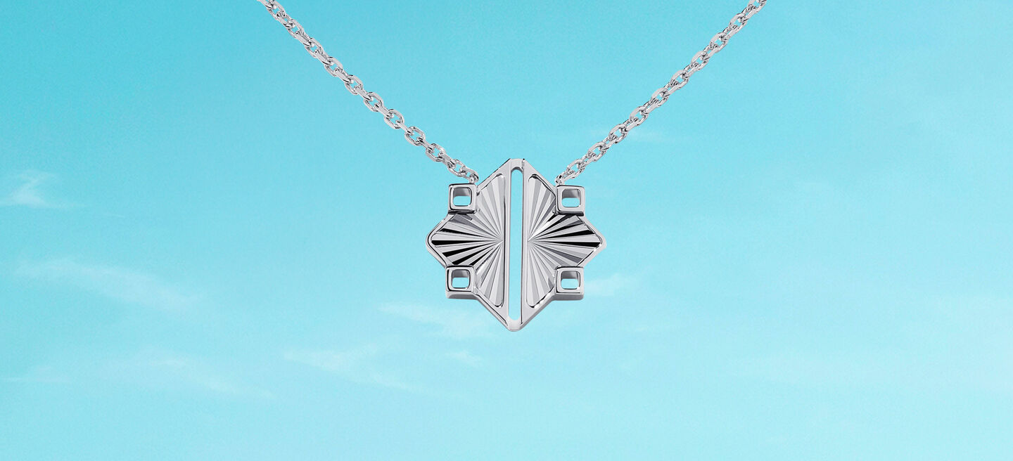 Birks Muse silver guilloche pendant necklace on a blue background.