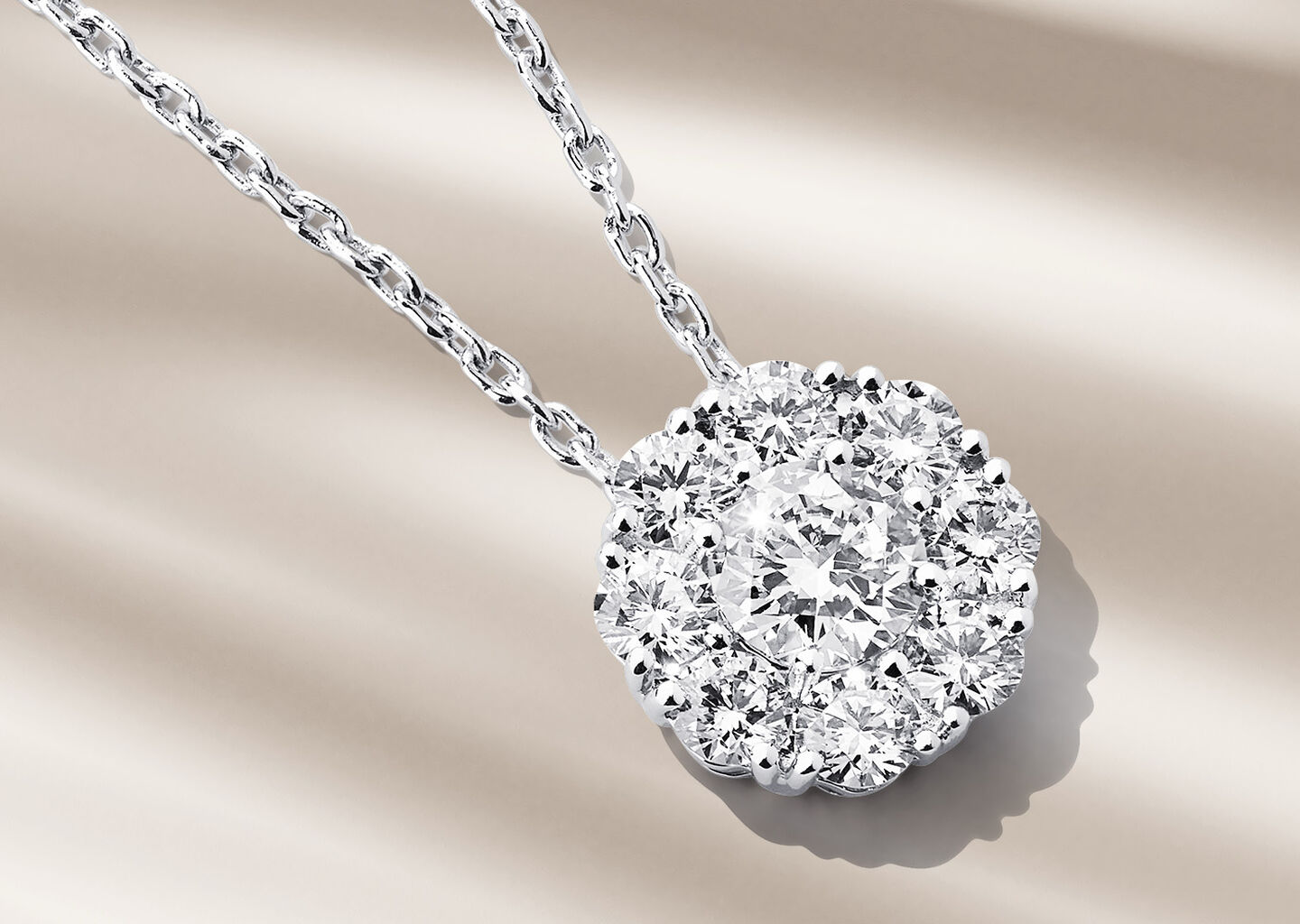 Birks Snowflake diamond cluster necklace on a beige background.
