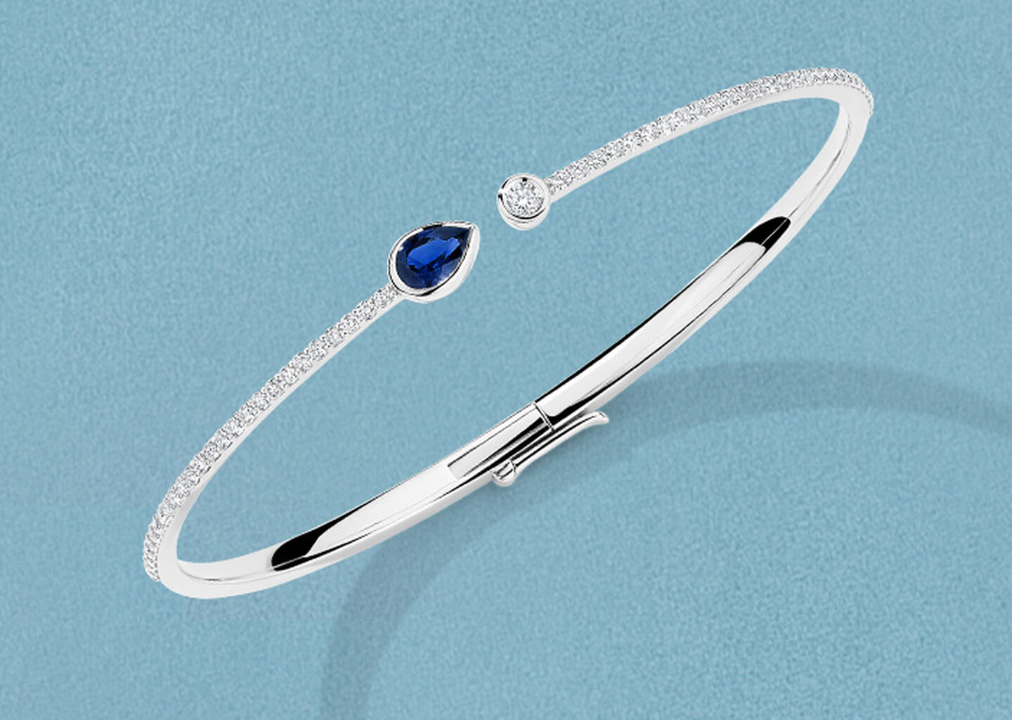 Birks Splash bracelet en or blanc avec saphir et diamants sur fond bleu.