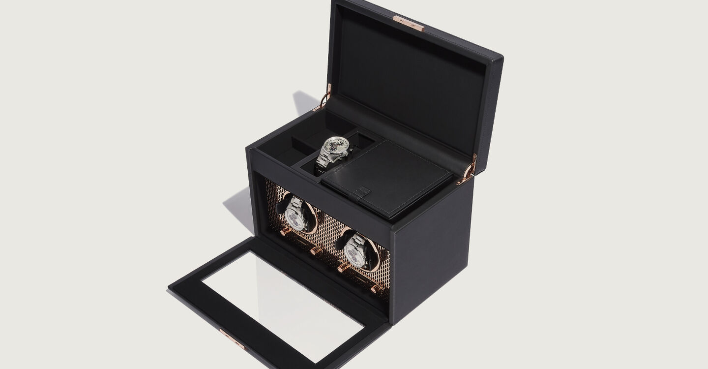 A black and gold double watch winder with upper storage container open