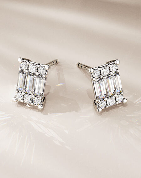 Birks Essentials diamond earrings on a beige background.