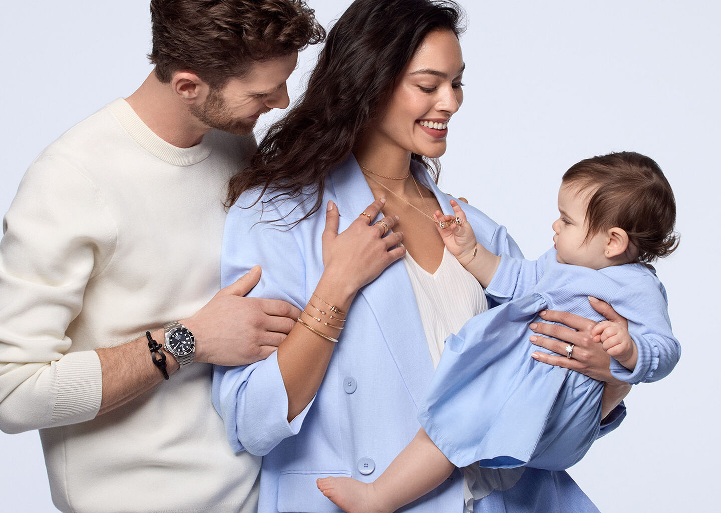 A family embracing, the parents are wearing jewellery from Maison Birks.