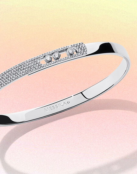 Bracelet en or blanc et diamants sur un fond rose et jaune.