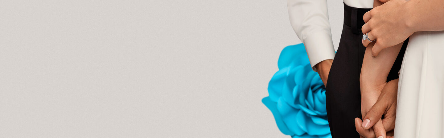 A couple holding hands in front of a blue rose