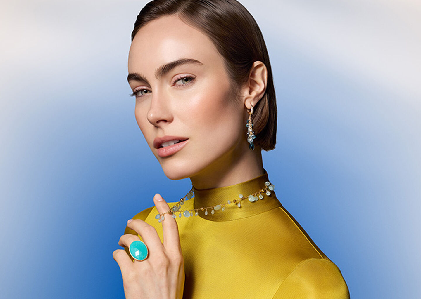 A woman wearing Marco Bicego jewellery on a blue background.