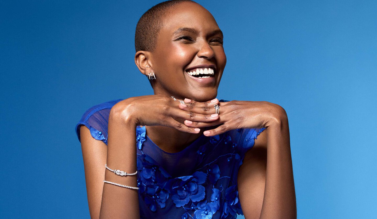 Une femme porte les bijoux avec diamants de Maison Birks sur un fond bleu.