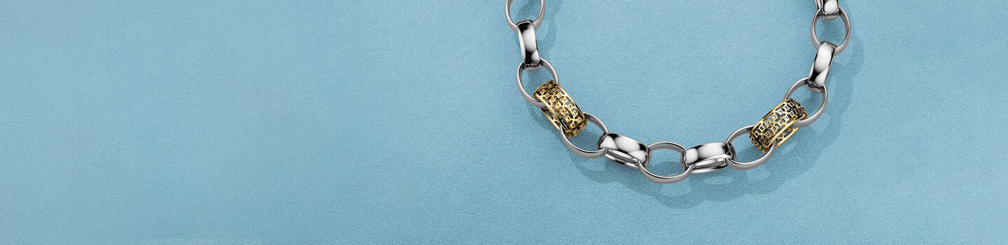 Birks Dare to Dream silver and gold bracelet on a blue background