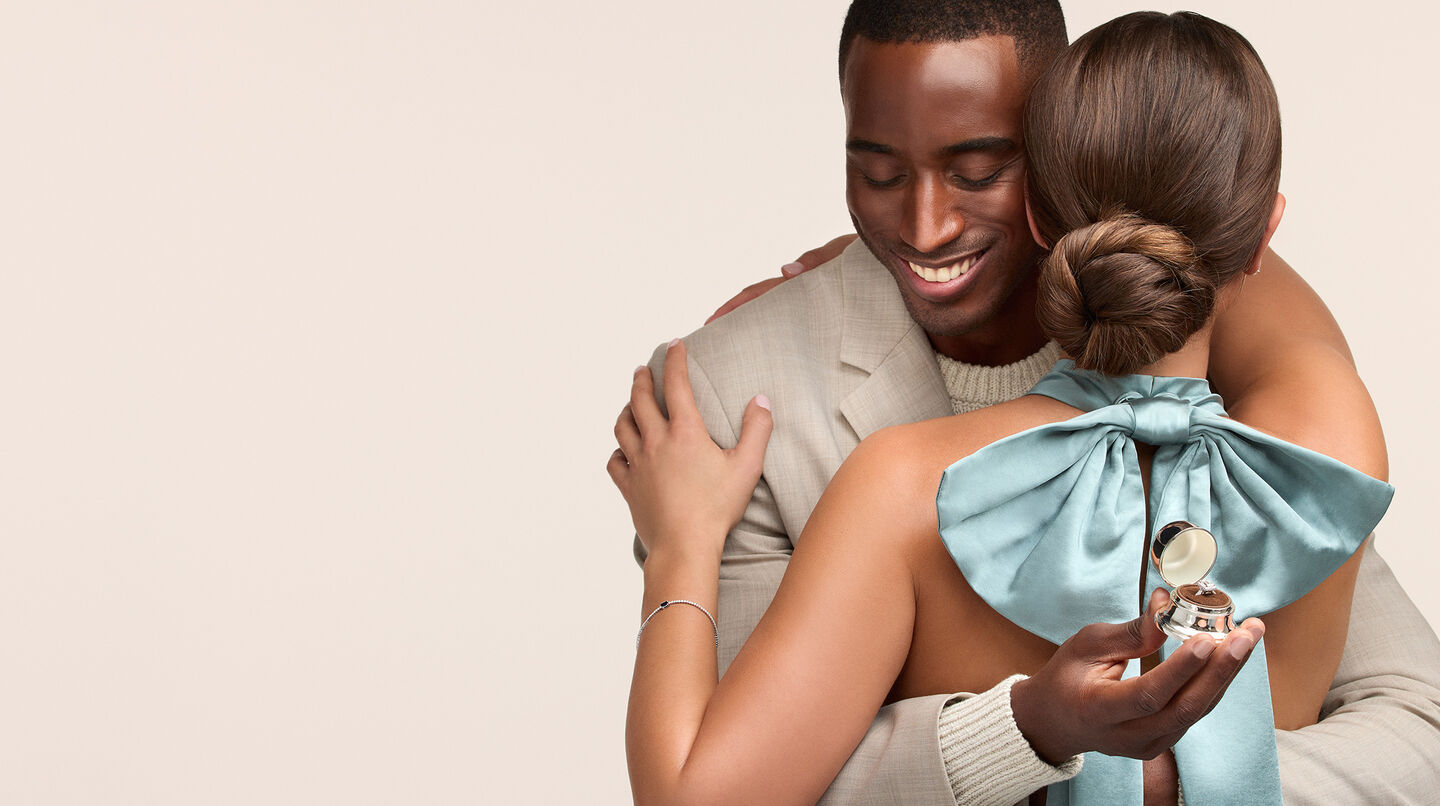 Un couple enlacé avec une bague de fiançailles Birks.