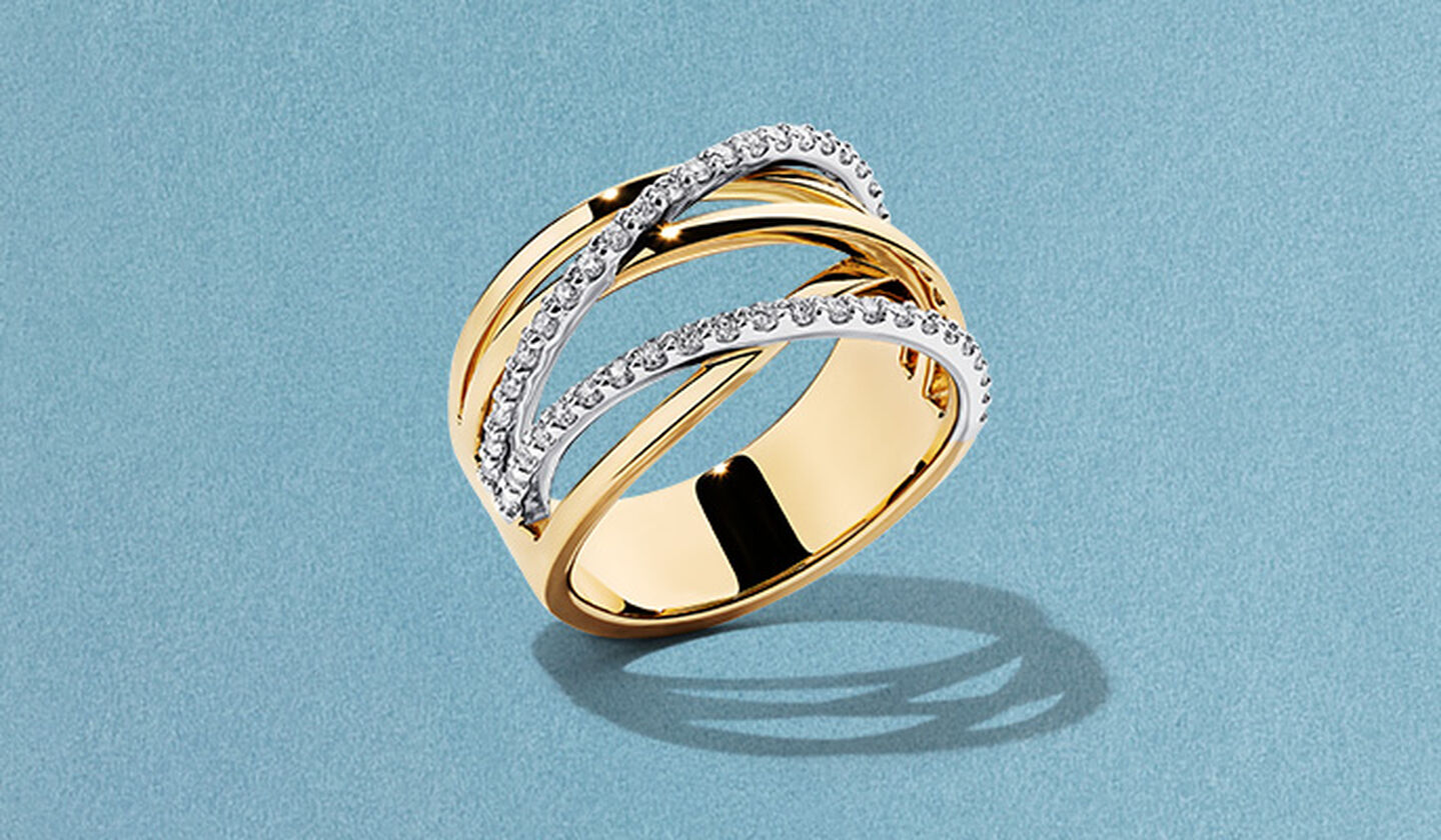 A yellow gold and diamond Ros&eacute;e du Matin ring on a blue background.