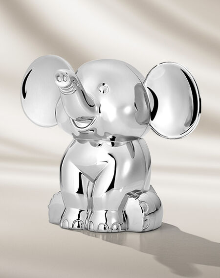Silver elephant coin bank a beige background.