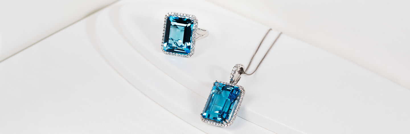 Two emerald-cut blue gemstones on a ring and necklace