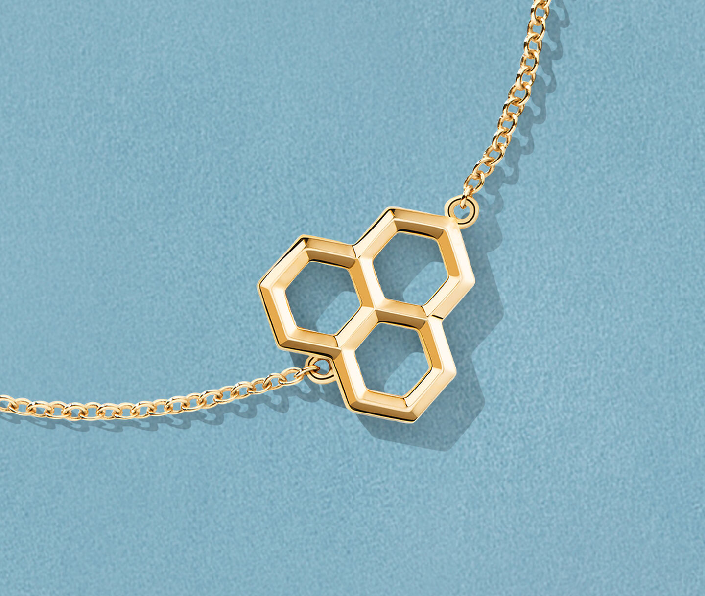 Bracelet en or jaune Birks Bee Chic sur un fond bleu.