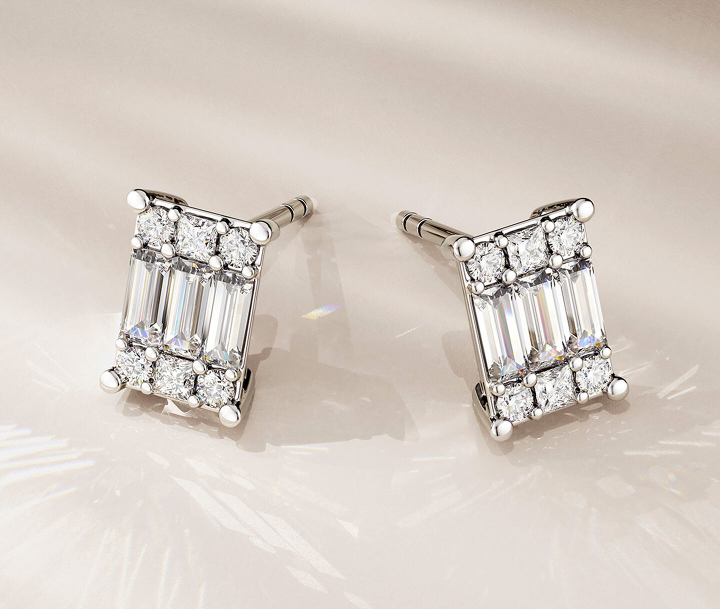 Birks Essentials diamond stud earrings on a beige background.