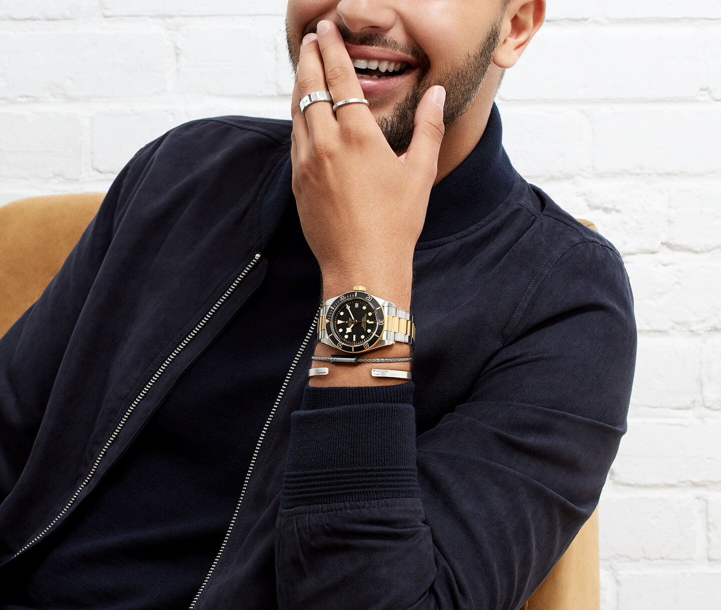 Un homme porte une montre Tudor Black Bay et les bracelets de le gramme.