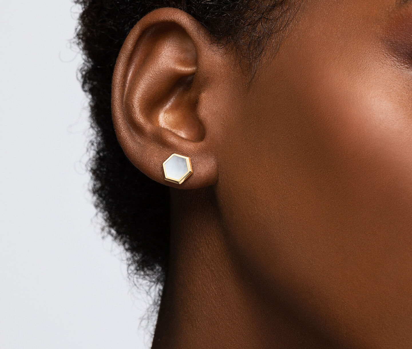 Une femme porte les boucles d'oreilles Birks Bee Chic avec nacre.