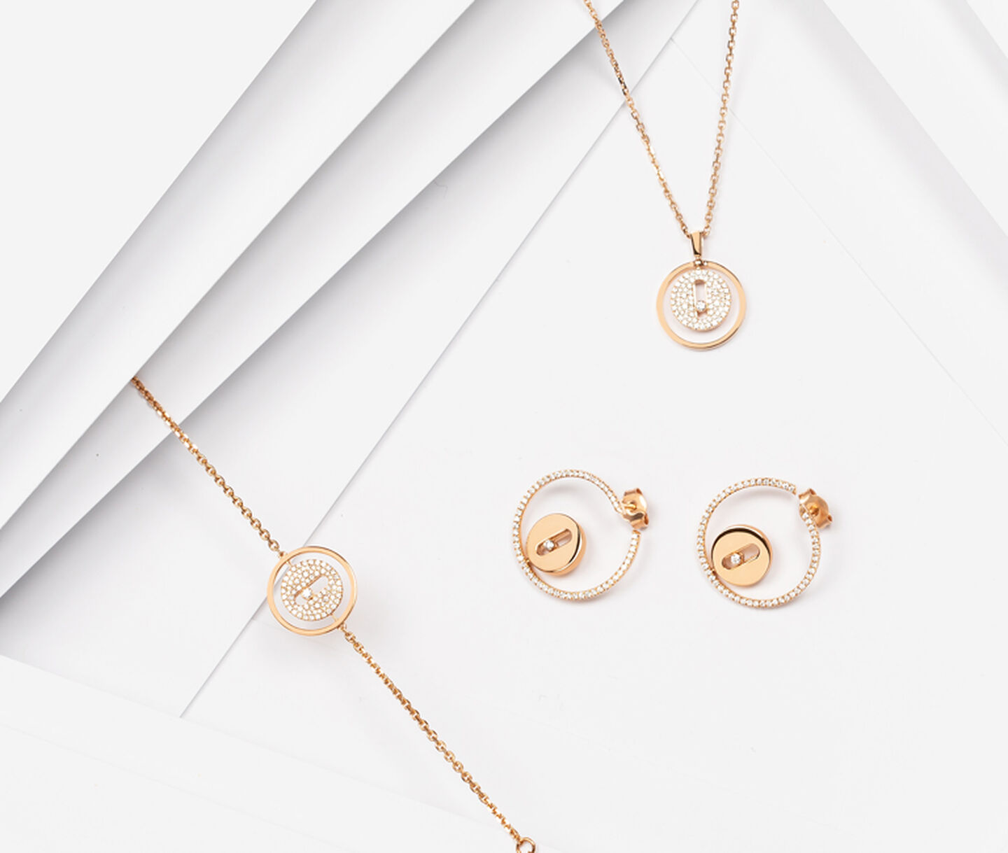 A collection of round gold and diamond pendant jewellery including earrings, a bracelet and a necklace