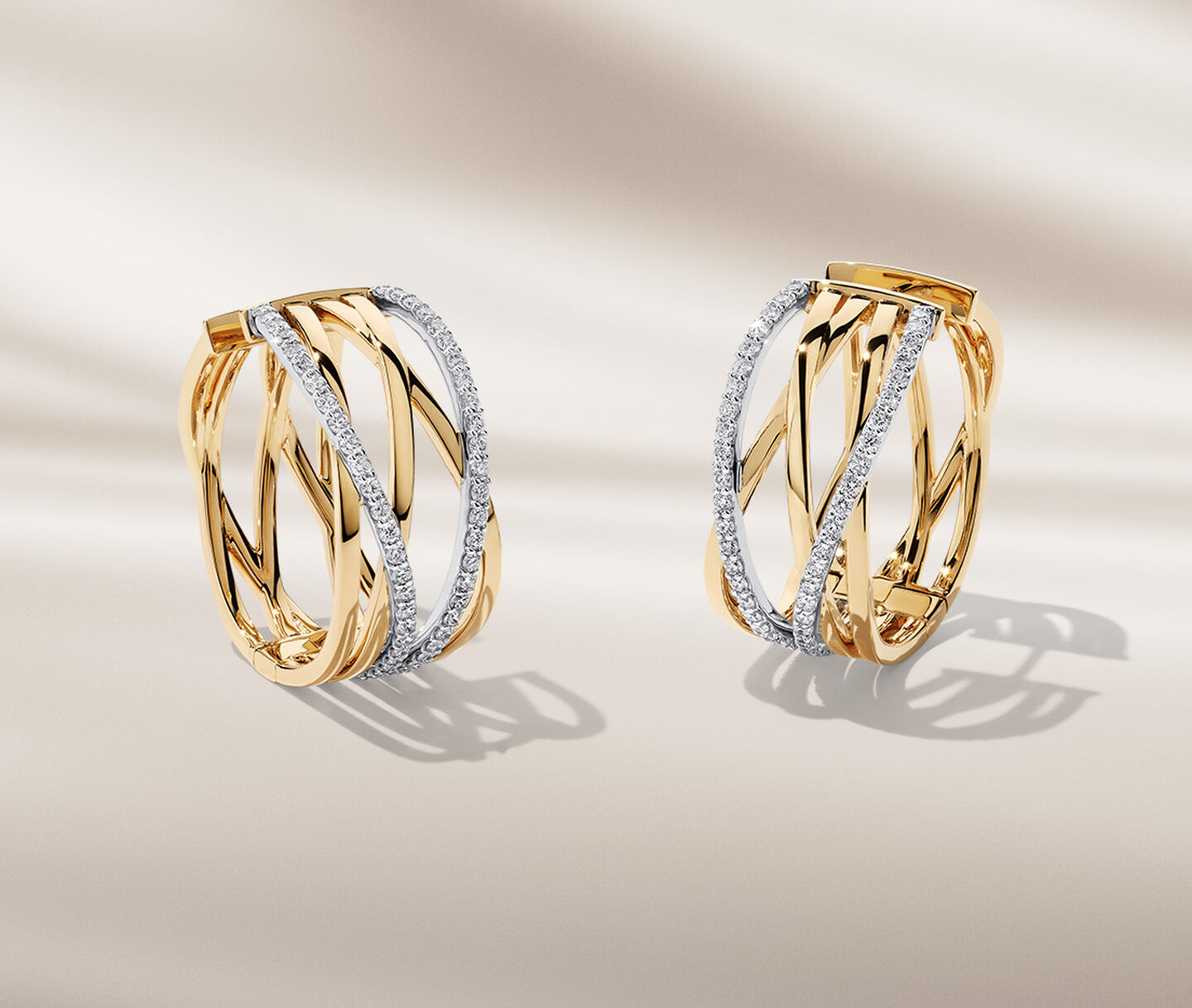 Birks Rosee du Matin diamond and yellow gold earrings on a beige background.